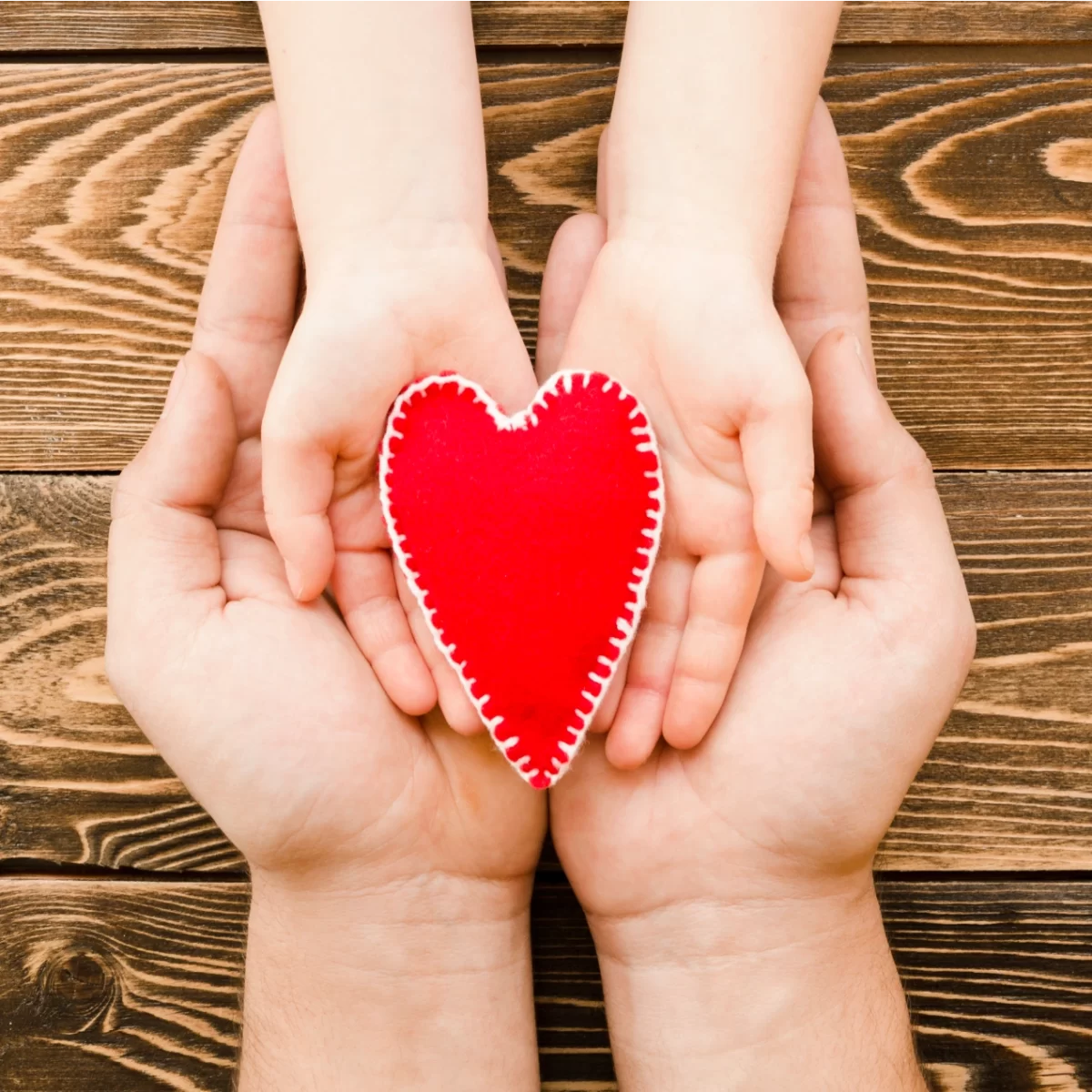 La imagen tiene un atributo ALT vacío; su nombre de archivo es people-holding-red-heart-hands-wooden-background-1200x1200.webp
